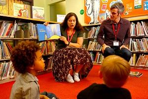Two adults reading a picture book to two children