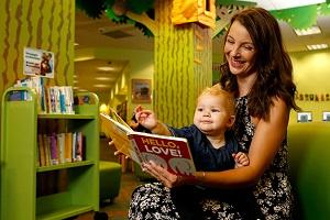 A woman reads a board book to a baby