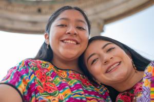 Two women leaning on each other and smiling