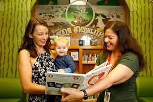 library staff holding a book open for a parent and child to view