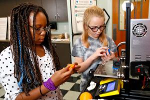 Two girls working with 3D printer
