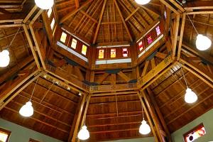 Wooden ceiling beams with hanging light fixtures and stained glass. 