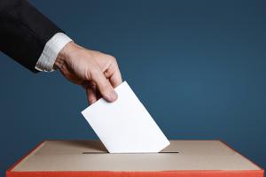 Hand placing a ballot in a box