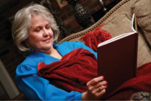 Woman reading a book while under a blanket