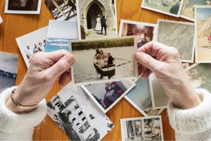 two hands holding up an old photo with other old photos in the background