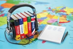 stack of language books with a headset over them over a global map