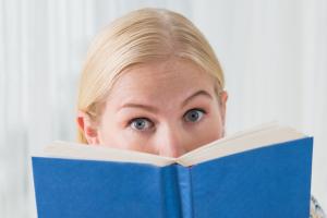 someone looking up from reading a book in front of their face with eyes wide open