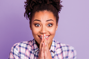 person with excited expression and hands clasped in front of them
