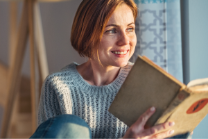 someone holding an open book and gazing in the light in the distance