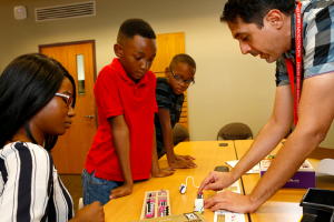 Librarian showing a woman and two boys a coding activity
