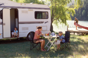 photo of campers with a camping trailer on a waterfront