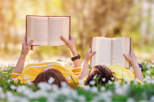 two people laying down and reading books outside