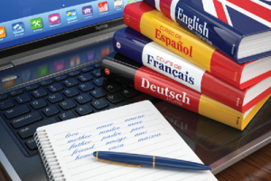 several different language books and a pen and notebook on a laptop computer