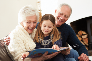 Grandparents Day photo of older couple reading with a young child