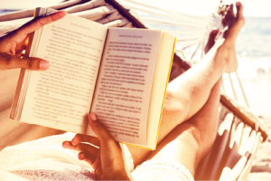 reading a book on a hammock next to the beach