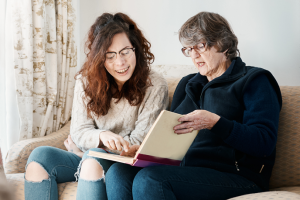 two people sitting down and looking at a book together