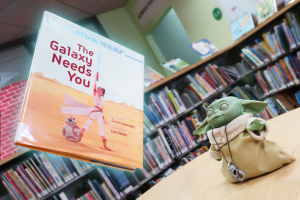 photo of small Grogu figure in the library with a hovering book 