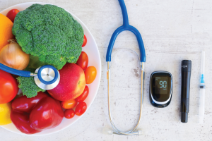 plate of vegetables next to a stethoscope and heart beat sensor
