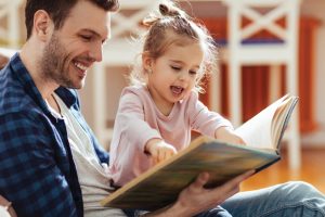 adult holding a child with an open book