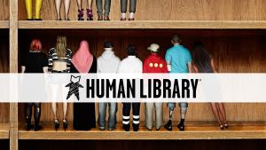The words Human Library are displayed in front of a bookshelf that has people standing in line as if they are books on a shelve. 