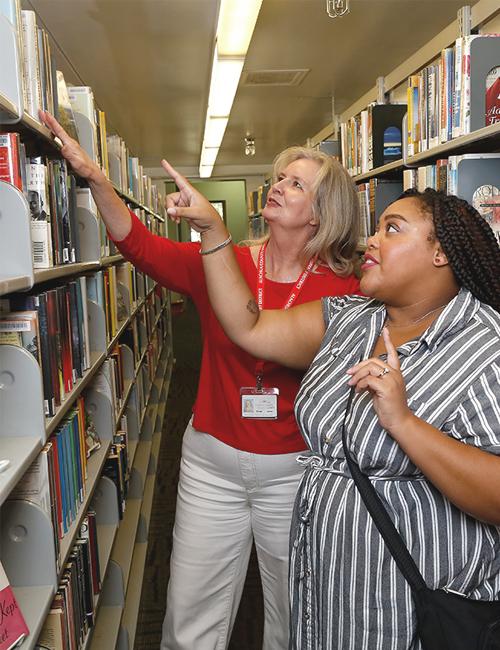 Library staff assisting patron in locating a book