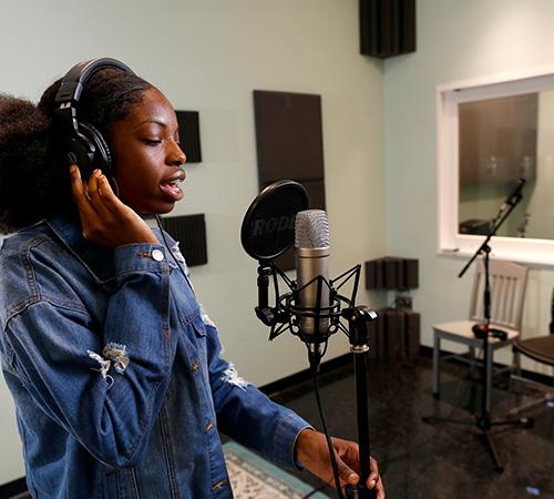 Girl singing into a microphone in the StudioSpace at Library Partnership Branch