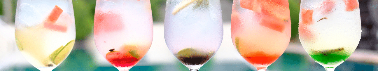 row of differently colored cocktails over ice in clear classes