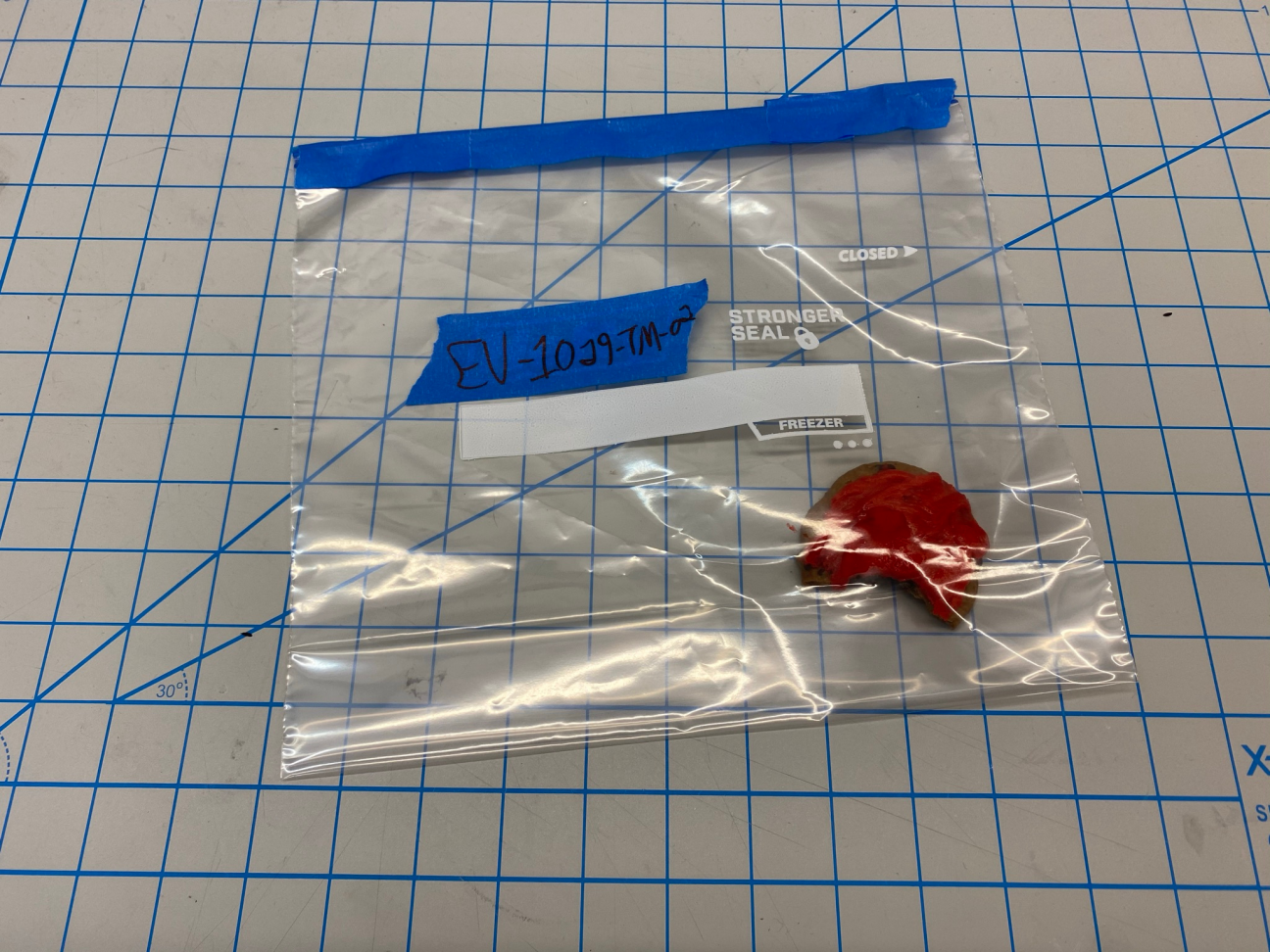 Evidence: Cookie Photo of an evidence bag, which contains a cookie with red frosting that was found on top of the victim's body. A bite has been taken.