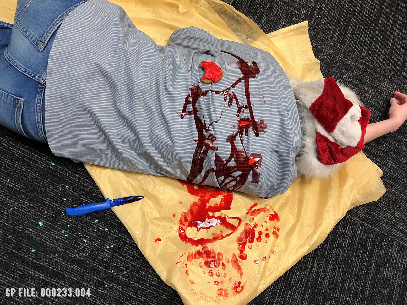 Evidence Photo 004 An angled photo of a dead body on top of a bloody tablecloth