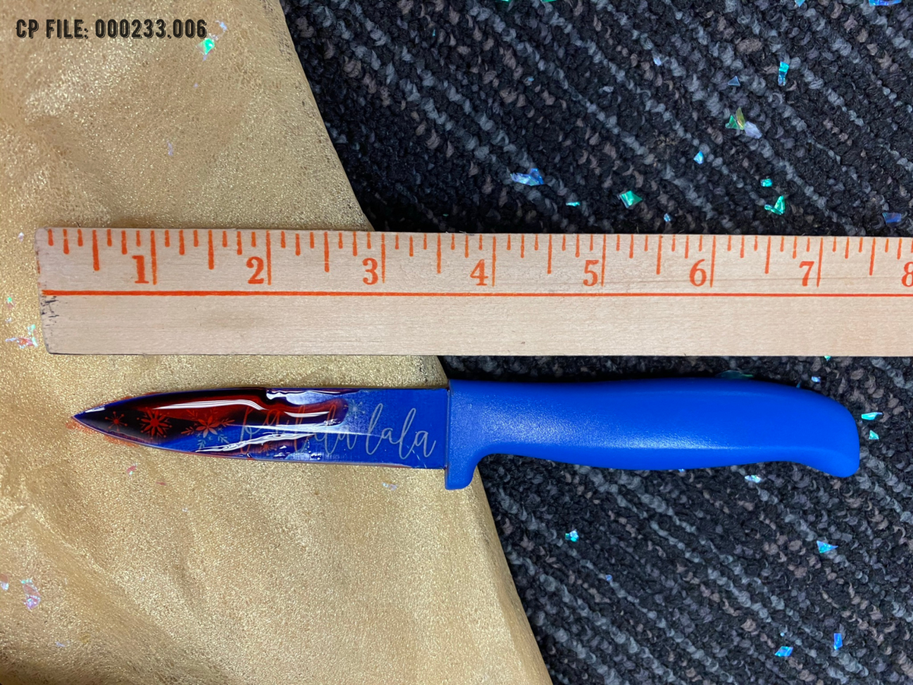 Evidence Photo 006 A close up of a bloody knife that says Fa la la la on it in cursive