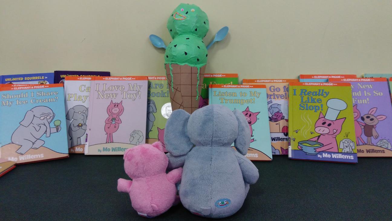 Gerald, Piggie, and Conezilla are surrounded by Mo Willems books