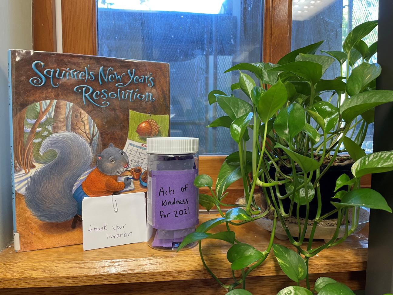 Picture of book "Squirrel's New Year's Resolutions" with jar labeled "Acts of Kindness for 2021" and a plant