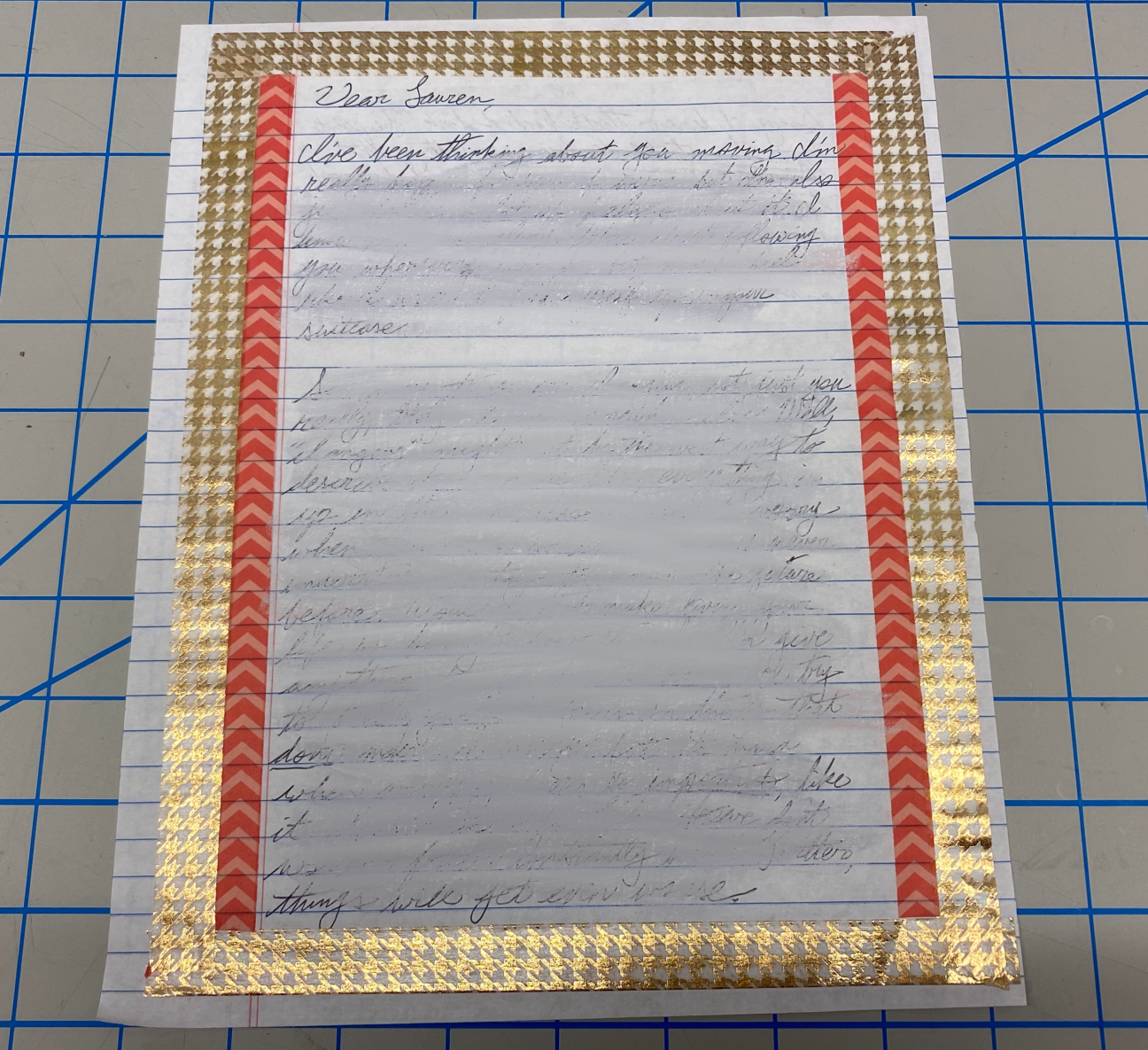 A blurred-out letter, with a washi tape border, on traditional lined paper.