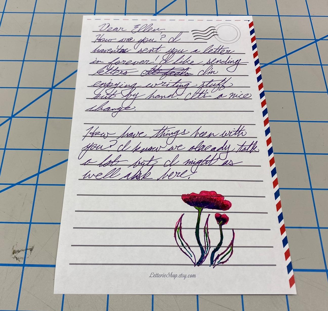 A letter written with gel pens on printed stationery, with a drawing of flowers on the bottom of the page.