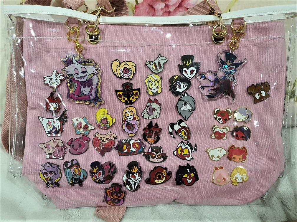 picture of a large ita bag with several Hazbin Hotel pins and charms