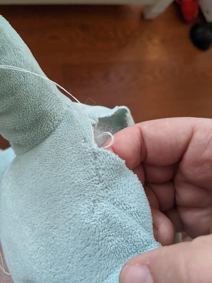 picture of a blue plushie lion with the neck being sewn up