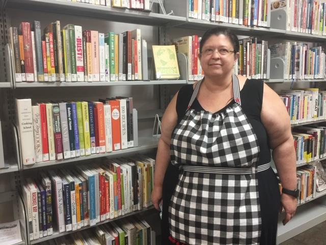 Attractive librarian modeling no-sew apron in front of cookbook shelves