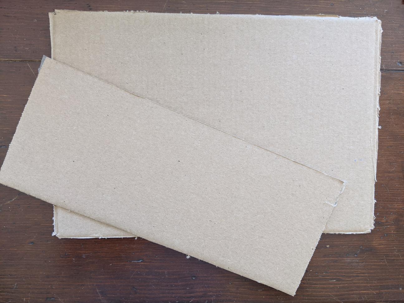 Two rectangular pieces of cardboard, one of which is thinner than the other.