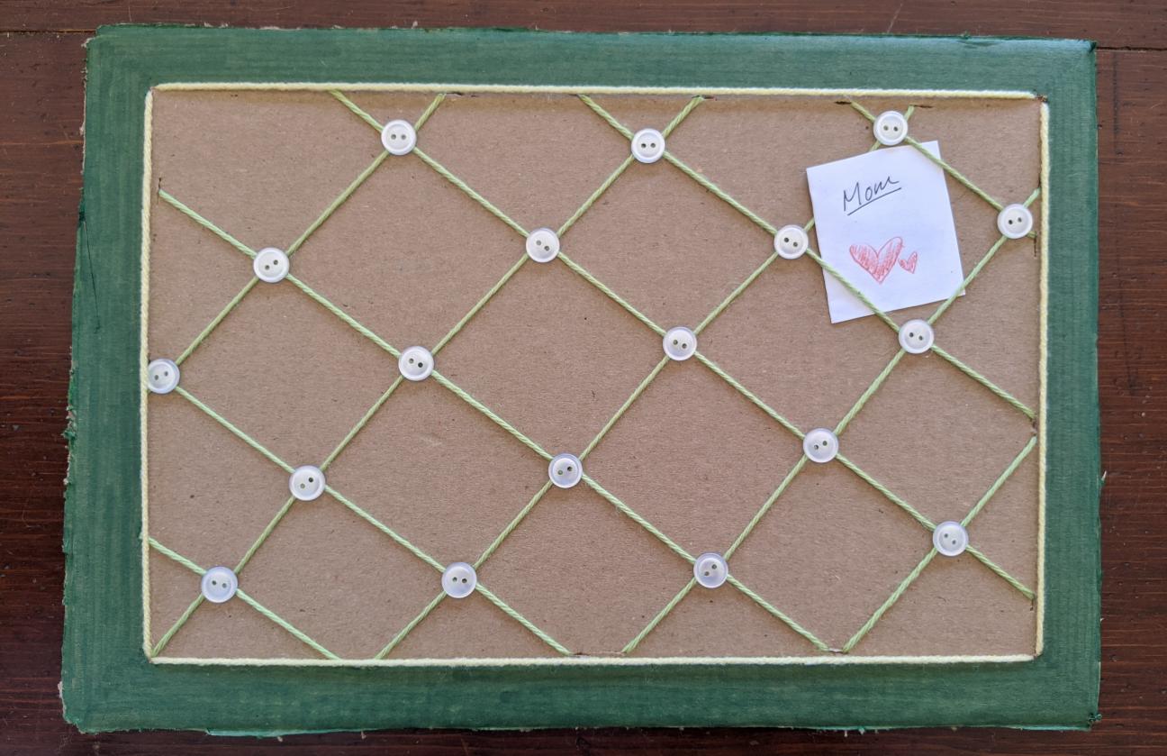 The photo board. The border has now been colored green, and small, shiny white buttons have been glued down at each yarn overlap point. The photo board. The border has now been colored green, and small, shiny white buttons have been glued down at each yarn overlap point.