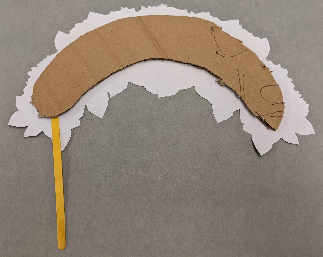 Adding the popsicle stick The same flower crown from the last photo, this time with a thin yellow popsicle stick protruding from the left side.
