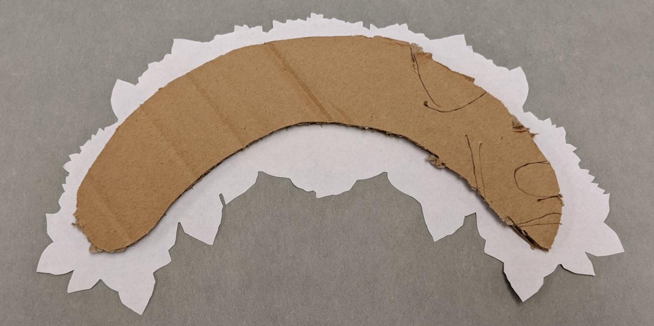 Cardboard backing The backside of a curved flower crown, with a smaller piece of cardboard over it.