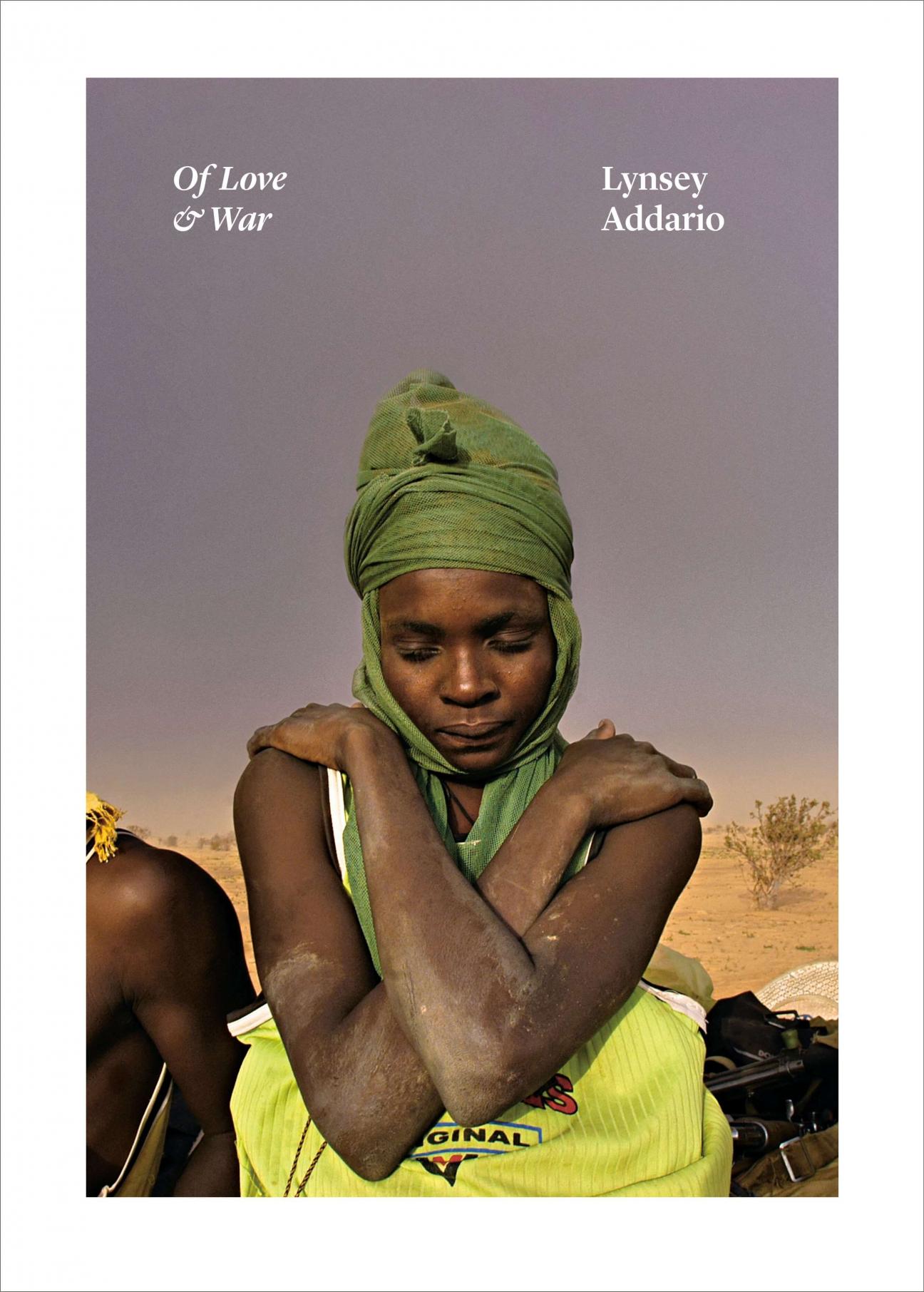 The cover of "Of Love and War" by Lynsey Addario, which has a photo of a Black woman in a green headdress with her arms wrapped around her shoulders. The title and author are at the top, and the photo is surrounded by a white border. 