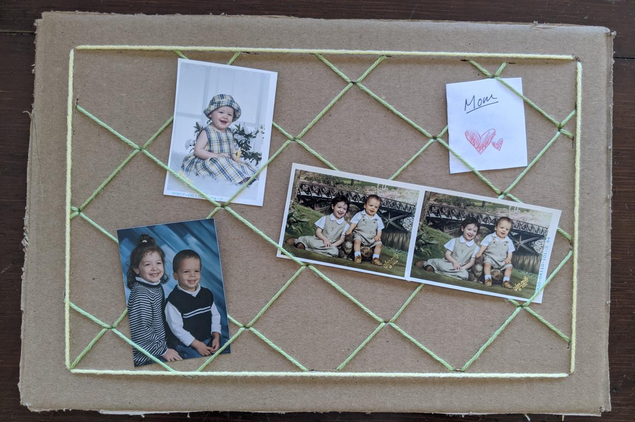 The completed photo board before added decorations. There are three small photos of young children and a folded note that says "Mom."