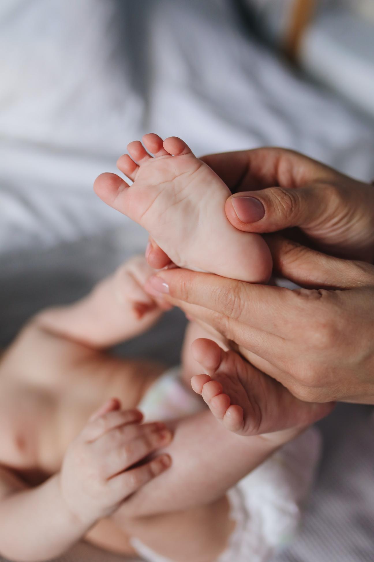 person holding baby's feet person holding baby's feet