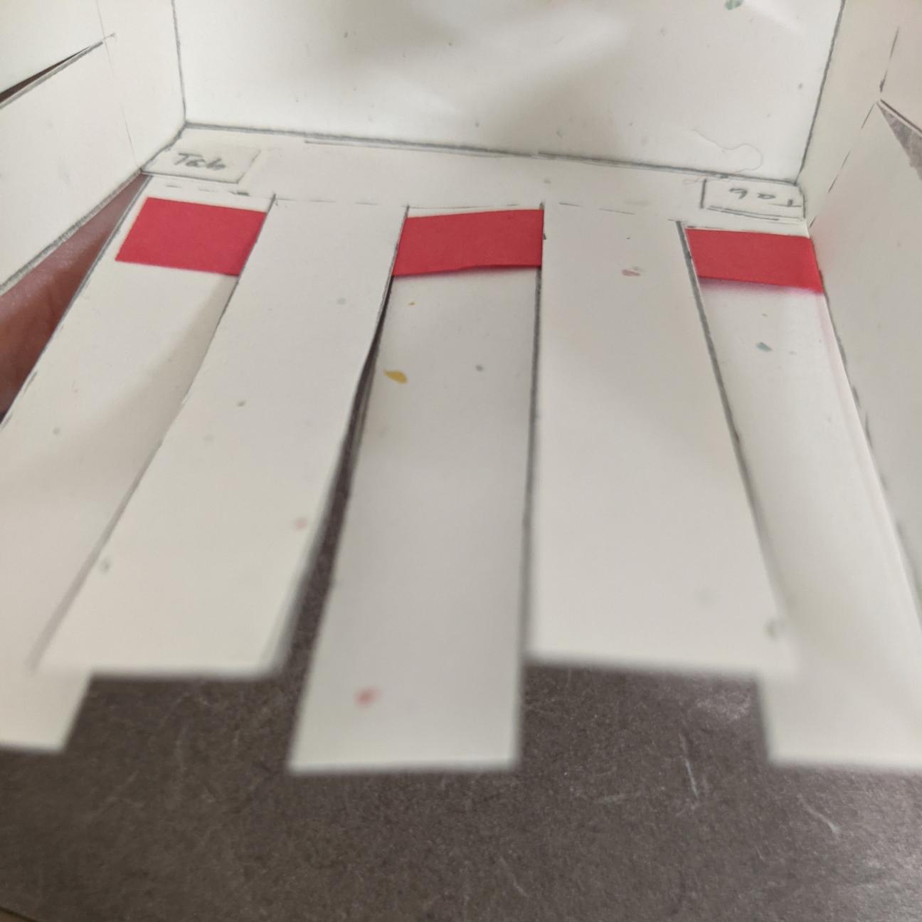 Begin weaving! The inside of the paper basket, with a red strip of paper woven between the white slats