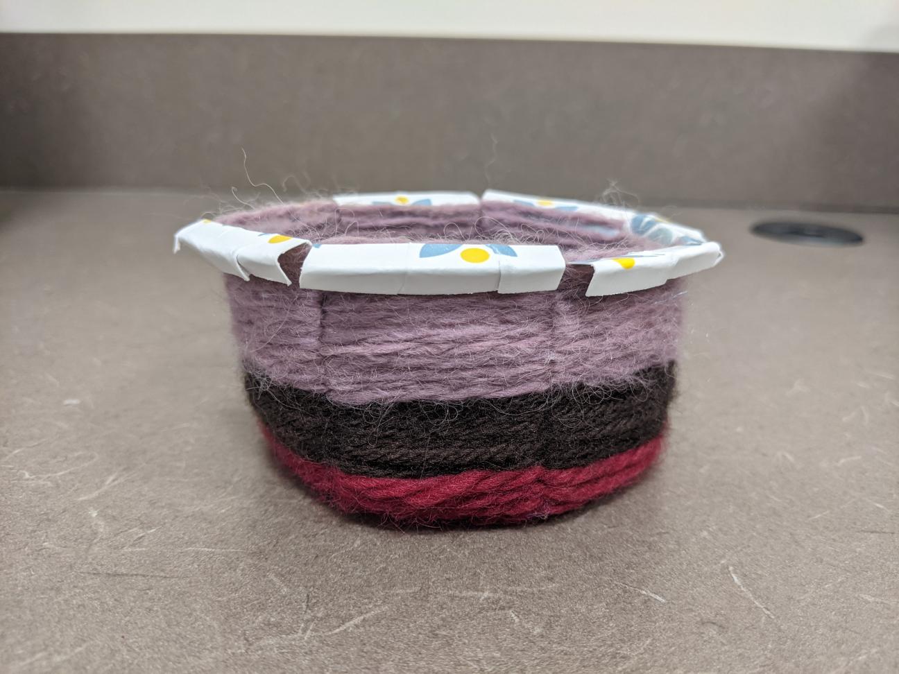 Finished yarn basket The finished yarn basket! It is small and has stripes of red, brown, and purple