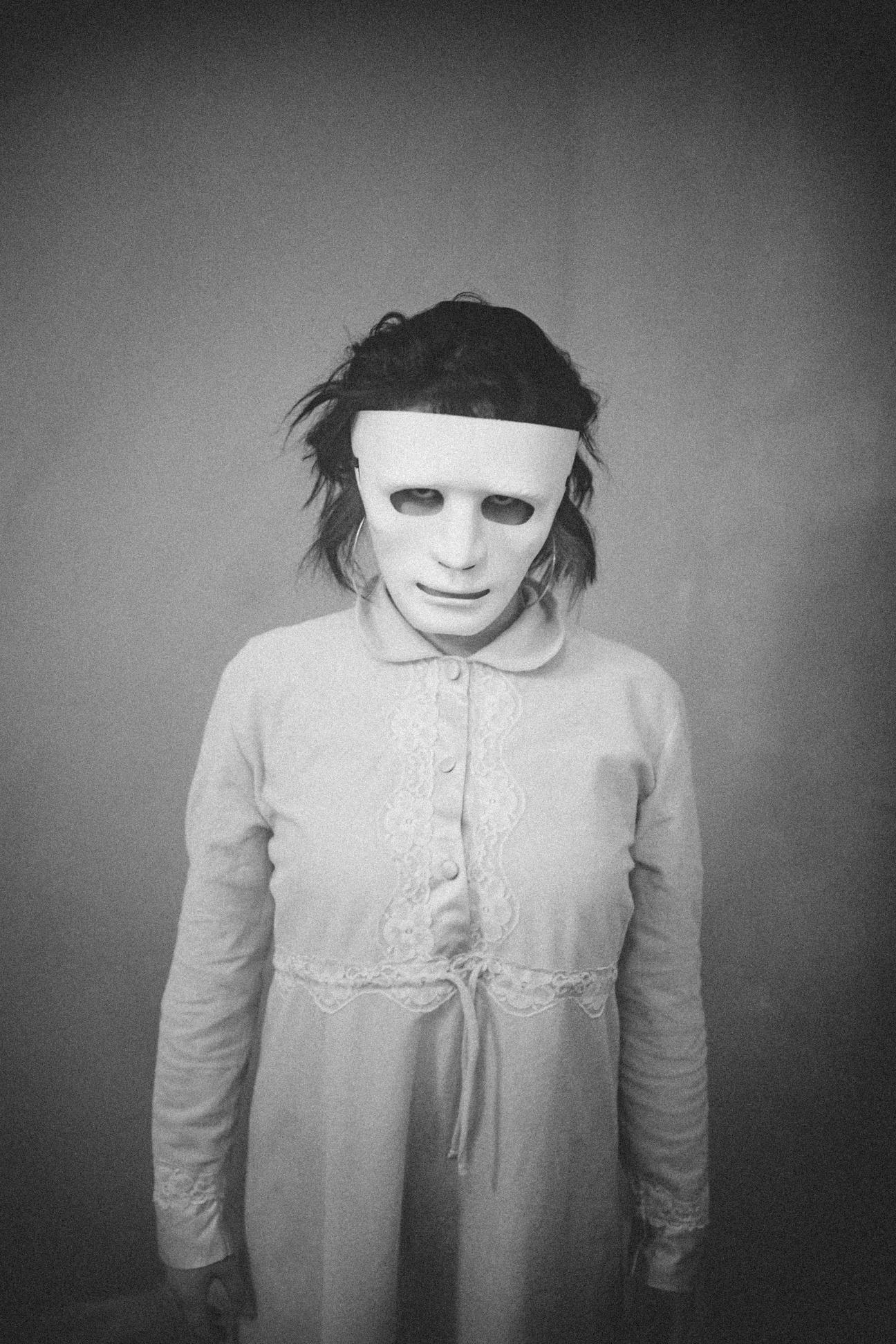 creepy girl in a plain dress wearing a blank mask