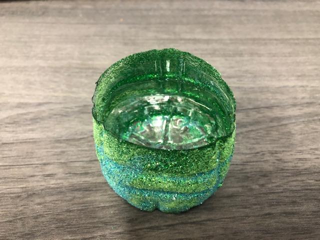 An image of the bottom half of a glitter covered water bottle filled about half full with water