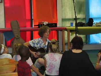 Katherine Archer playing the guitar and singing to children in Hawthorne library
