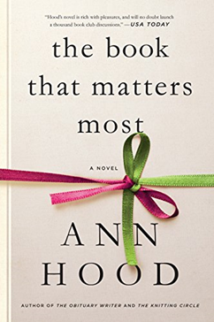 An image of a white book with pink and green ribbon tied around it in a bow.